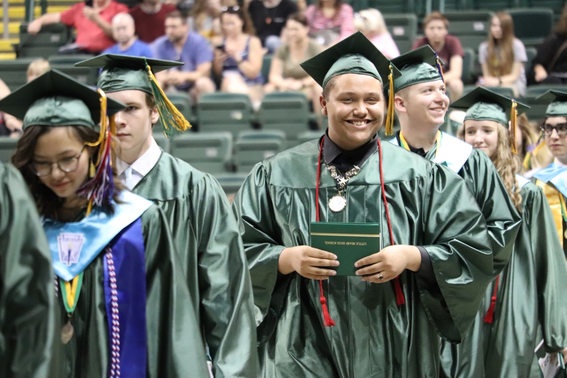 graduate smiling and holding diploma