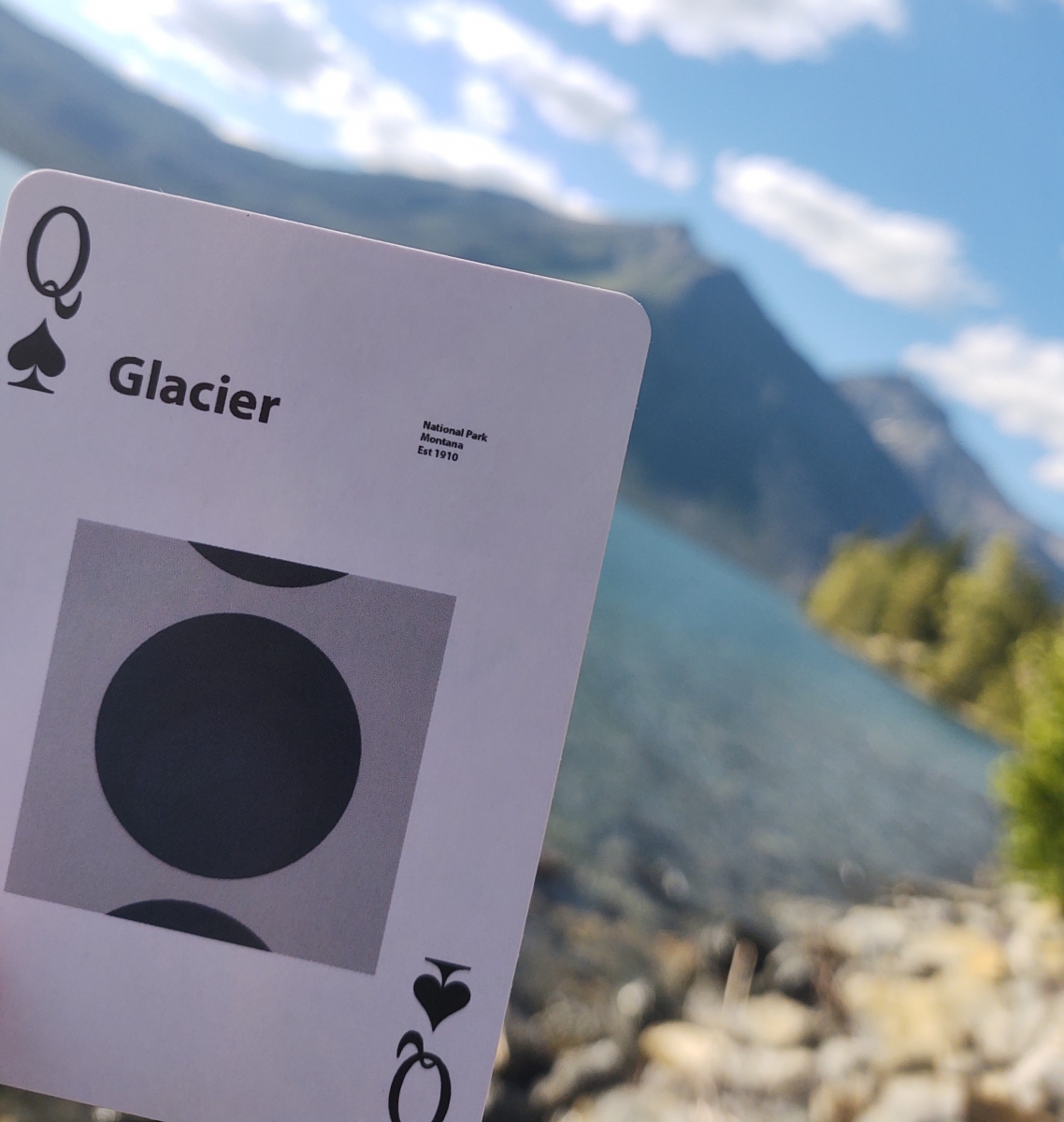 playing card in front of mountains and a lake