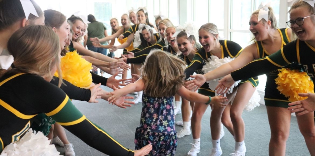 young girl running through a high five tunnel of cheerleaders